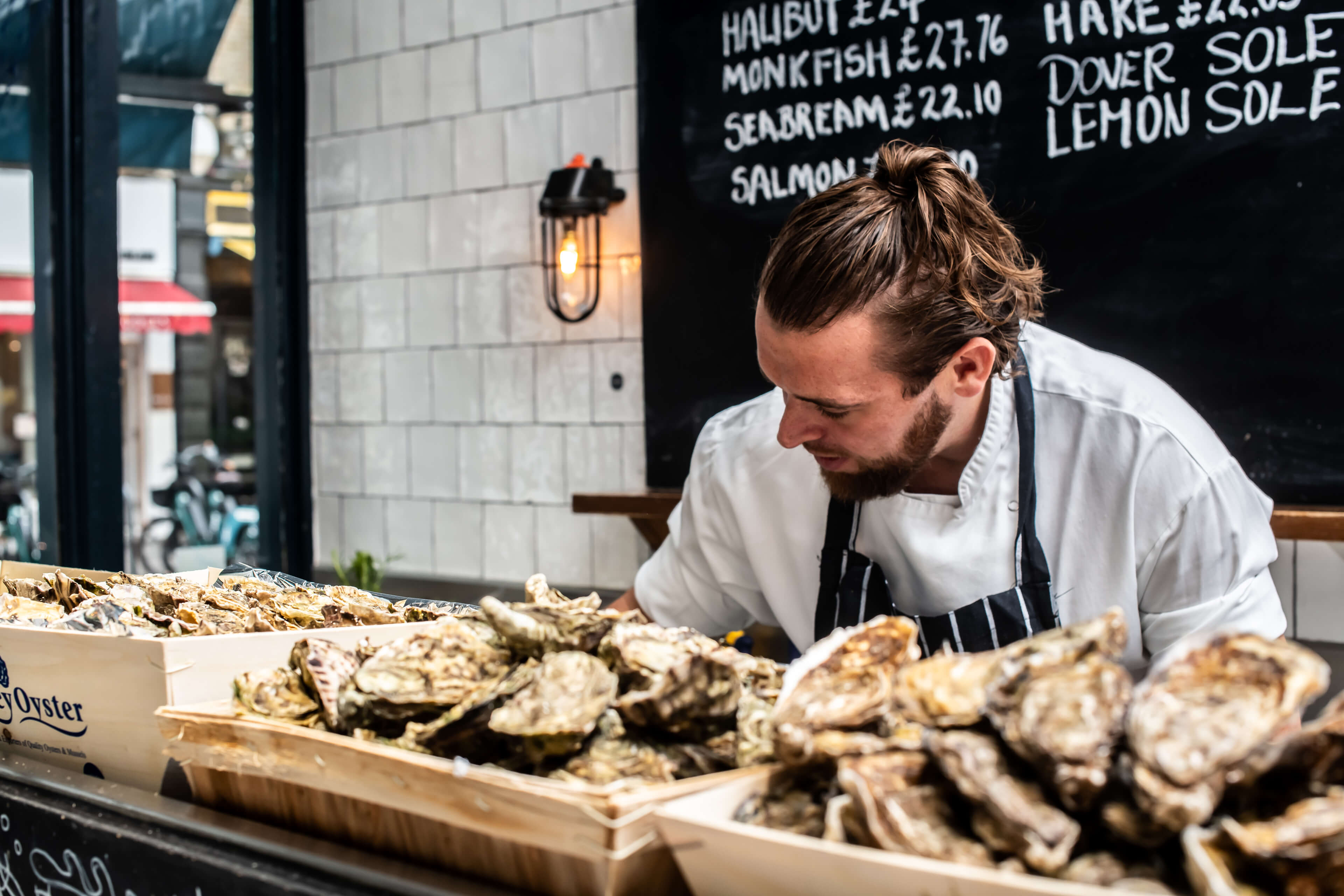 A Fishworks fishmonger behind trays of oysters and crabs