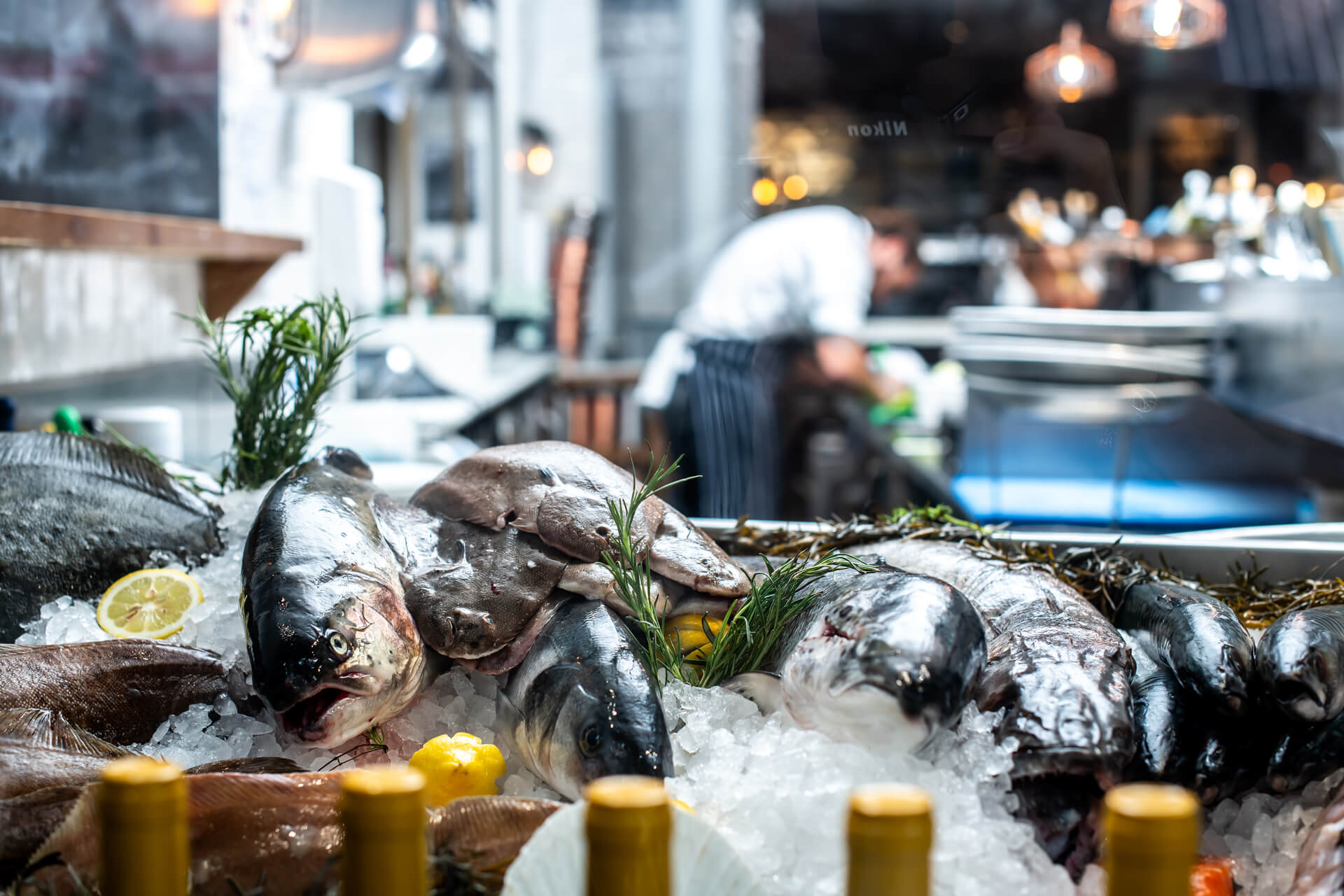 Fresh fish laid on a bed of ice with a Fishworks fishmonger in the background
